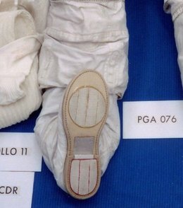 The sole built into Neil Armstrong's Apollo 11 suit, turned up in the pre-flight laydown. A flat oval, a few light stripes, and a metal shank at the heel. Detail of NASA S69-38889.