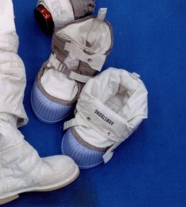 The lunar overboots from the same photograph, name tag ARMSTRONG, lying next to the suit boot. Blue silicone soles, horizontal ribs. Detail of NASA S69-38889.