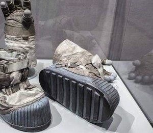 The bottom of a lunar overboot, turned up in a museum case. The ribs run across the silicone sole. The boot at the left is the same kind, seen from the front.